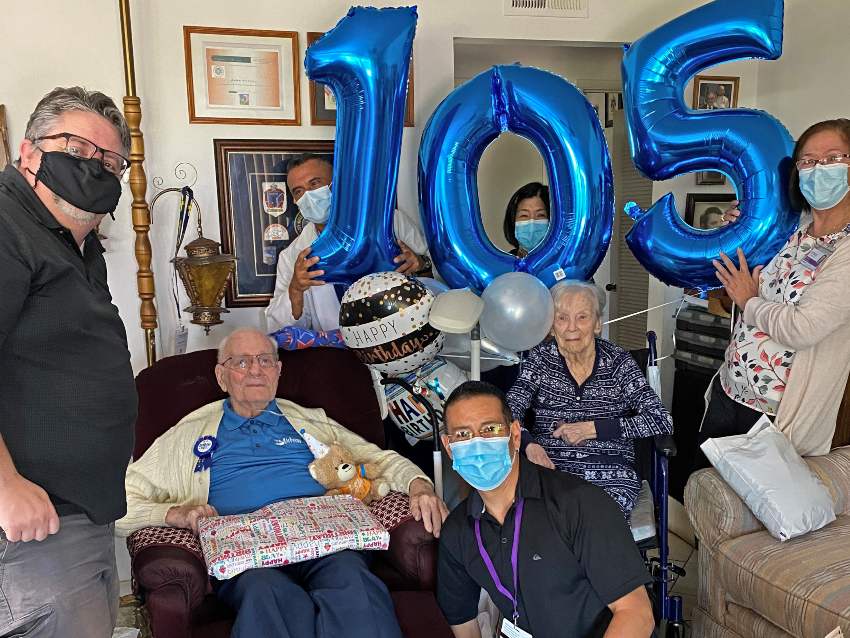 The VITAS team with John and his wife and blue balloons spelling out 1-0-5