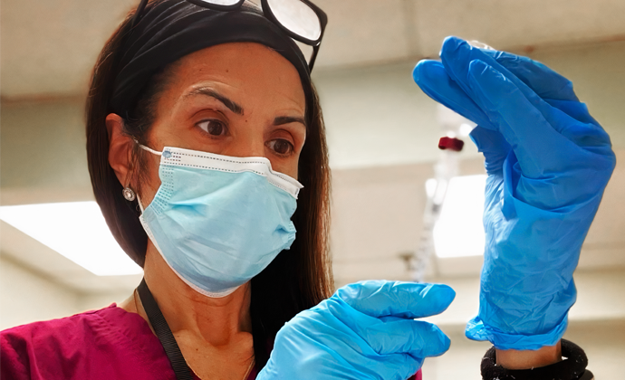 Inpatient LPN Denise Papagoda, wearing a medical mask, prepares a syringe.