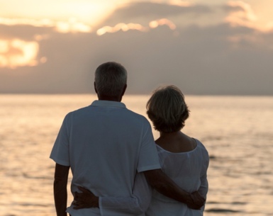 A couple looks out at a sunset on the ocean