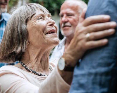 An older woman embraces and smiles at a loved one
