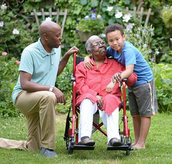 A woman rests outside in a wheelchair as her grandson hugs her