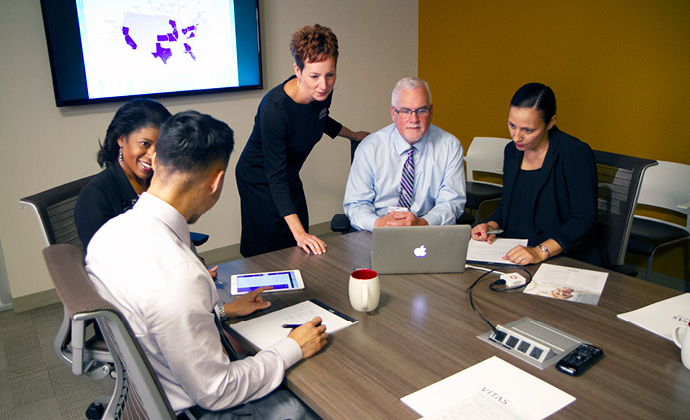 A team of healthcare professionals talk at a conference table