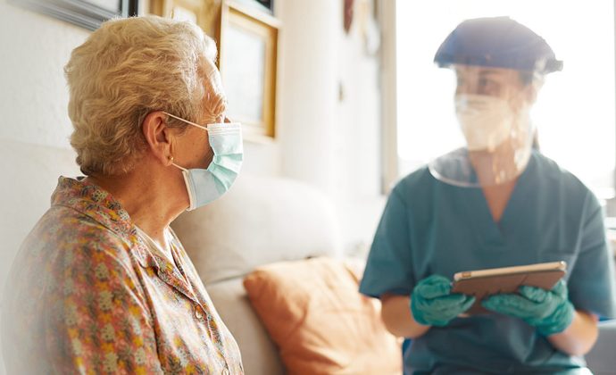 A clinician talks with a patient as both sit on a sofa