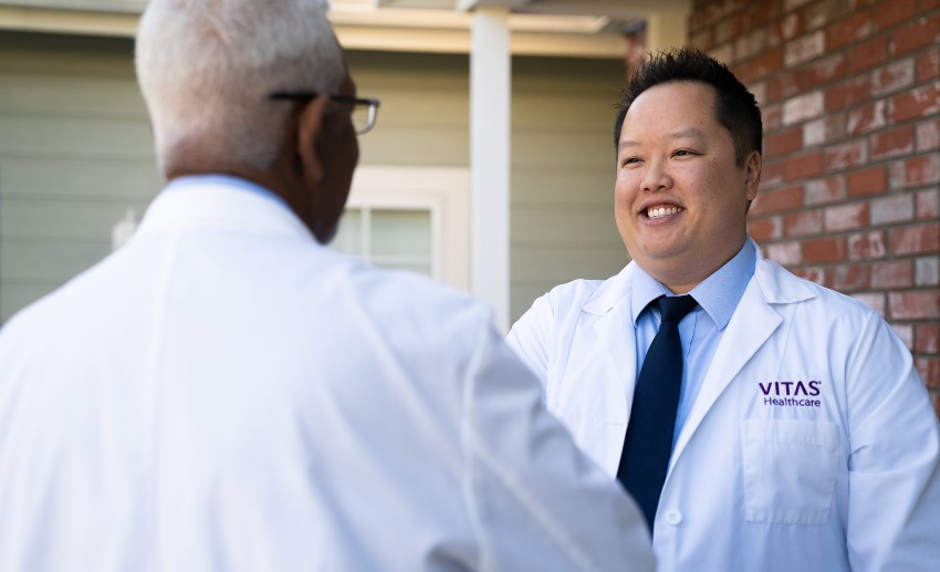 Two physicians in white coats greet each other